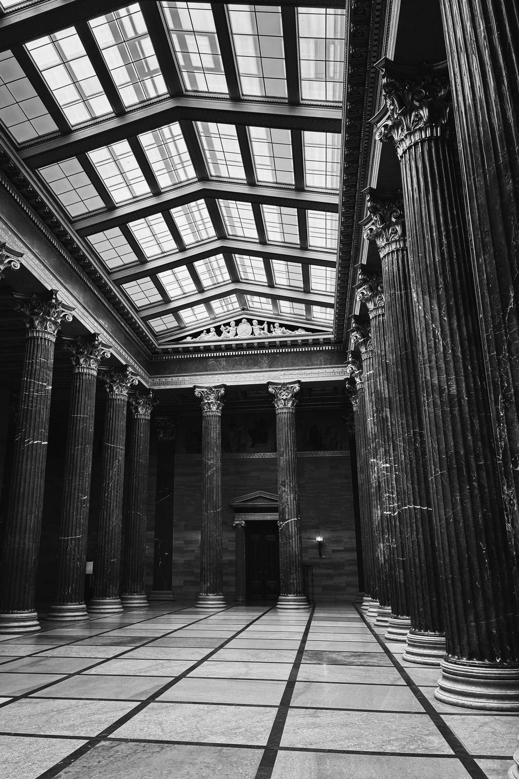 An empty grand civic hall with marble columns and a skylight