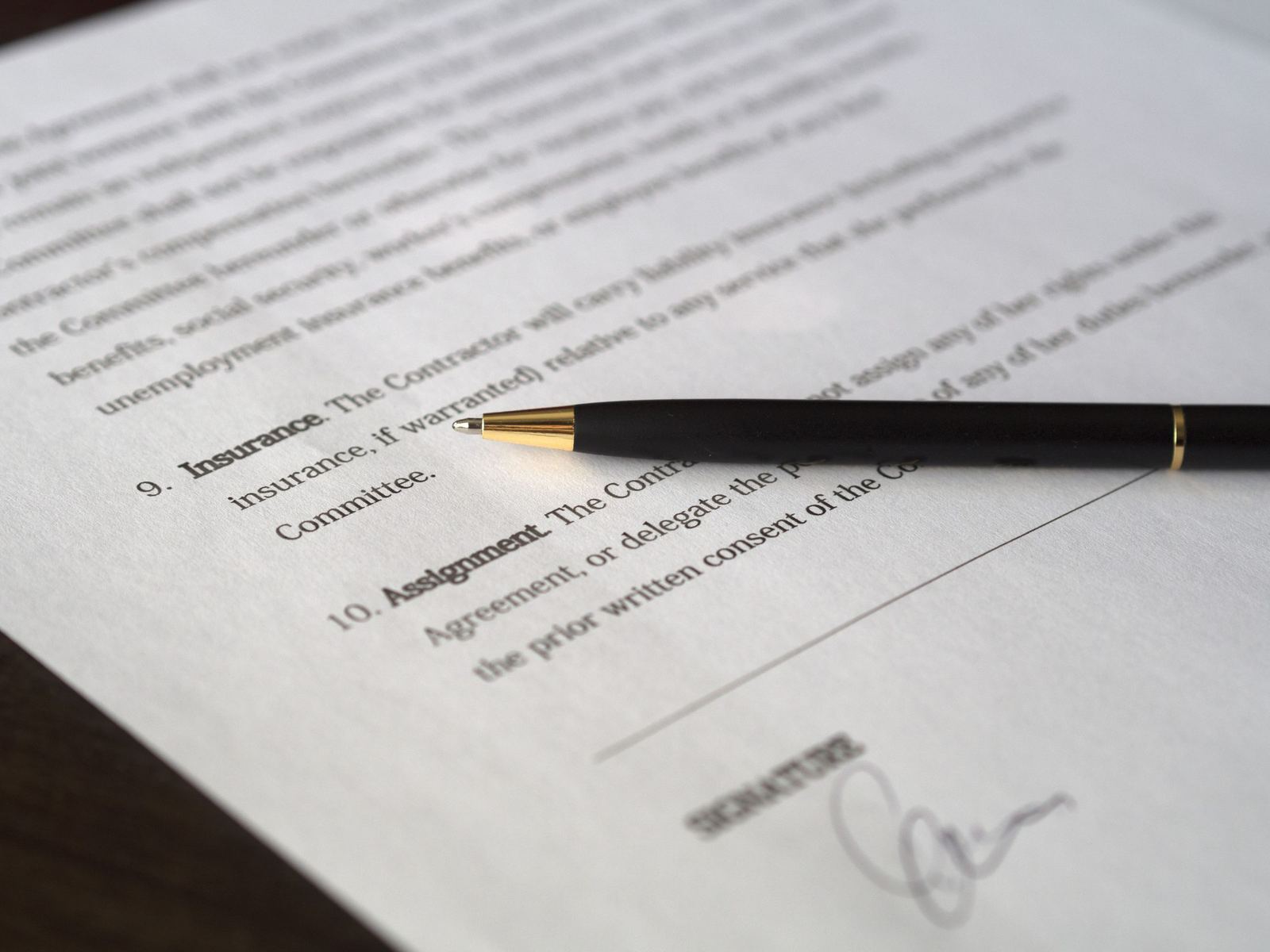 A pen resting on a contract beside the signature line