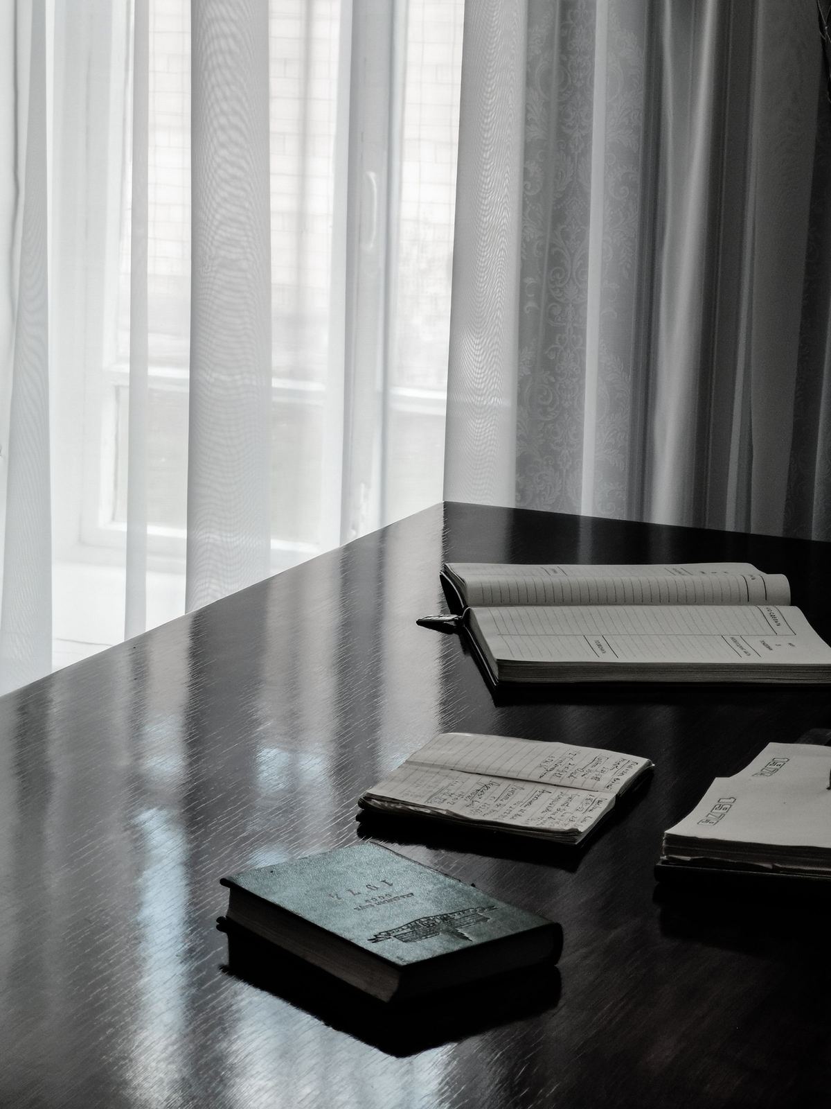 A quiet desk with ledgers by a curtained window